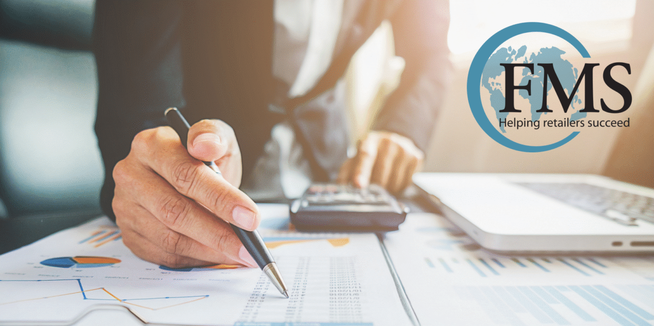 A person reviews financial charts and uses a calculator at a desk, with a laptop nearby. The FMS Solutions logo and slogan “Helping retailers succeed” are displayed in the upper right corner, reflecting expertise in investment strategies for retailers.