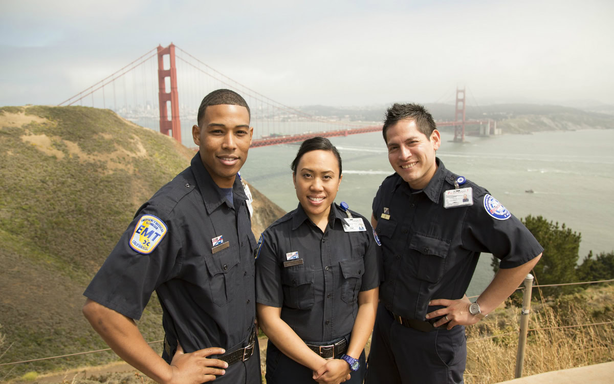 Three EMTs in uniform stand smiling with the Golden Gate Bridge and San Francisco Bay in the background on a partly cloudy day, celebrating Covalent Health’s seventh year on the Inc. 5000 list.