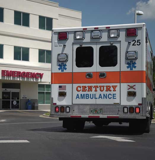 A Century Ambulance, part of a recent ambulance acquisition by ProTransport-1, is parked outside a hospital emergency room entrance on a sunny day.