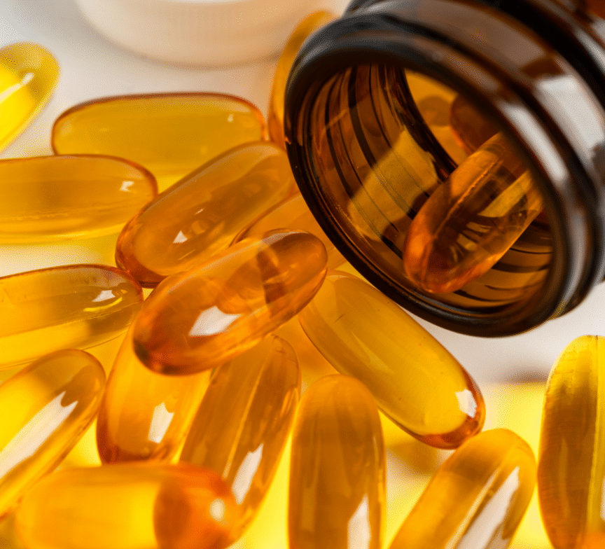 A brown glass bottle from Icelandirect is tipped on its side, with several yellow translucent gel capsules spilling out onto a white surface.