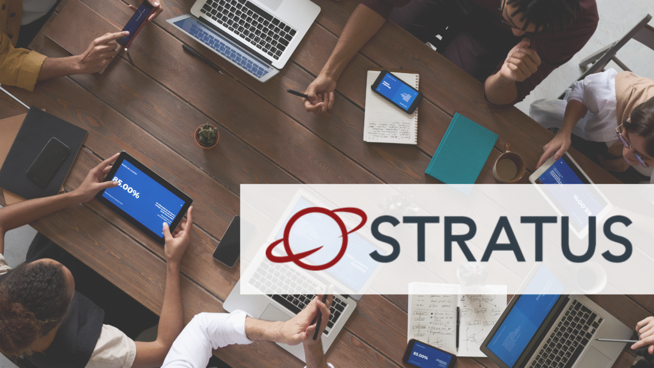 A group of people work together at a table with laptops, tablets, and notebooks. Highlighting partnership, the STRATUS logo with a red planet icon is overlaid on the lower part of the image.