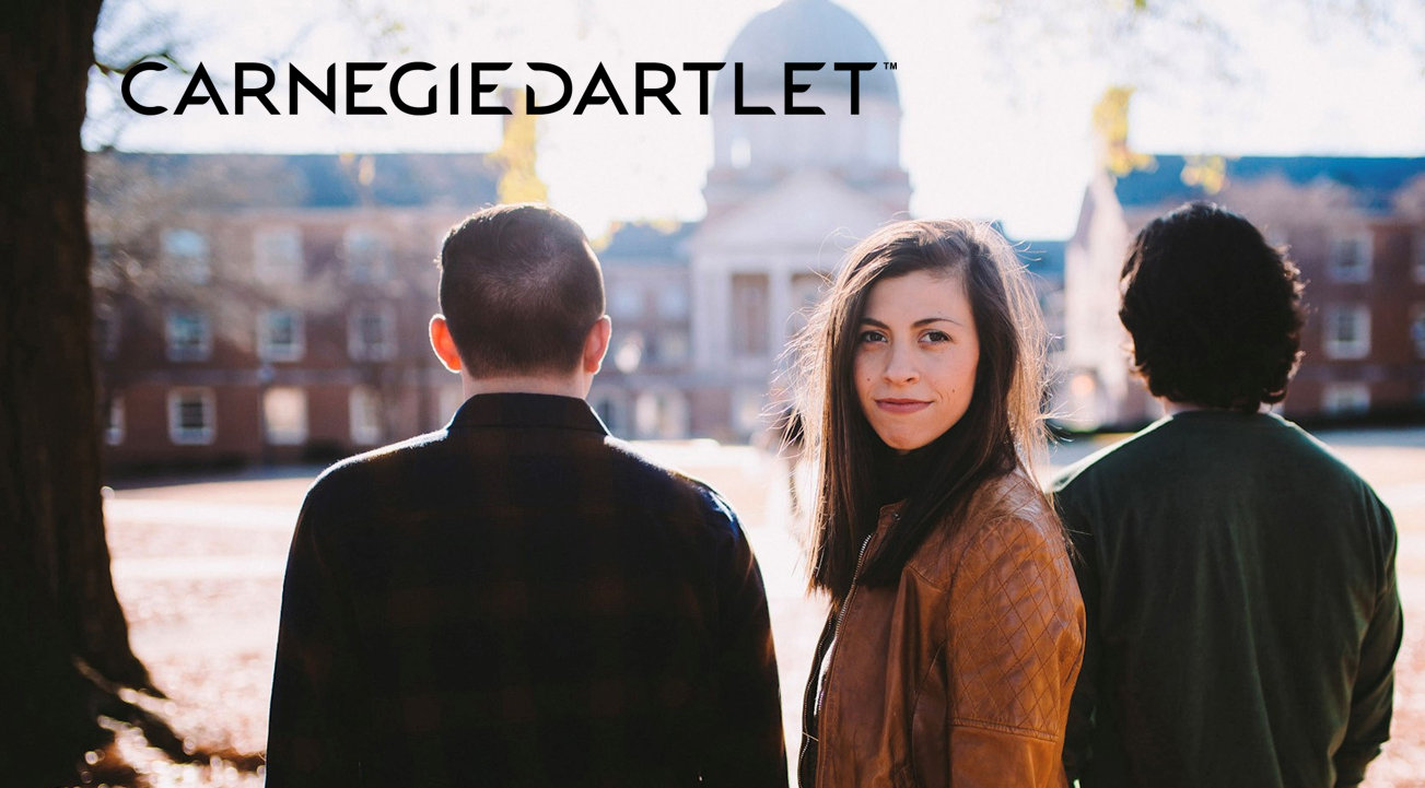 Three people stand outdoors near a university campus; one woman faces the camera while two men have their backs turned. The Carnegie Dartlet logo, symbolizing investment in education, appears at the top of the image.