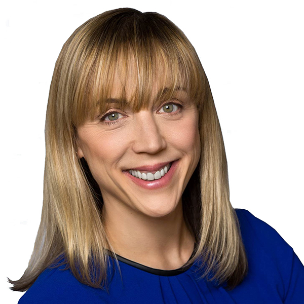 A smiling woman with straight blonde hair and bangs, wearing a royal blue top, is pictured against a plain white background.