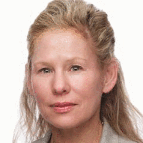 A middle-aged woman with blonde hair, wearing a light gray blazer and a light-colored top, posing for a professional headshot against a plain white background.